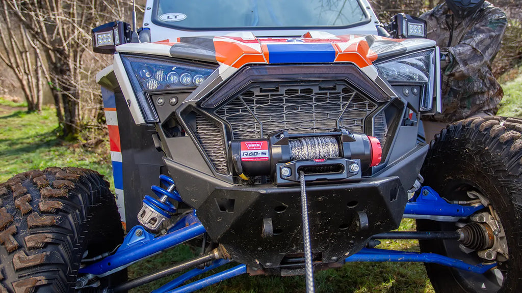 WARN R60-S 6,000 lb ATV/UTV winch shown in grassy outdoor terrain